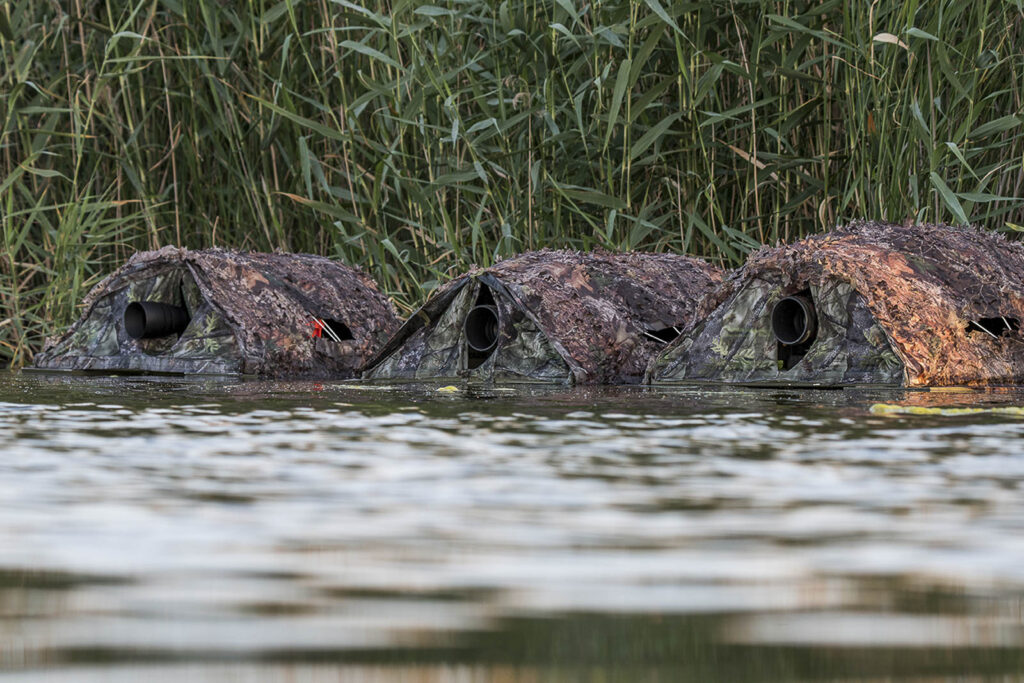 Tres hidrohides camuflados con redes de hojas sobre el agua para fotografía de aves en la Laguna de El Taray.