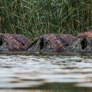 Tres hidrohides camuflados con redes de camuflaje en el agua de la Finca El Taray, Toledo, preparados para fotografía de aves a nivel del agua.
