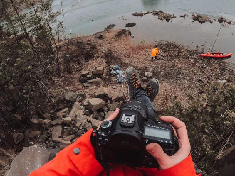 Punto de vista de un fotógrafo con chaqueta roja sosteniendo una cámara reflex frente a un lago con islas, turismo fotográfico con Wild Spain Travel y Aveshide.